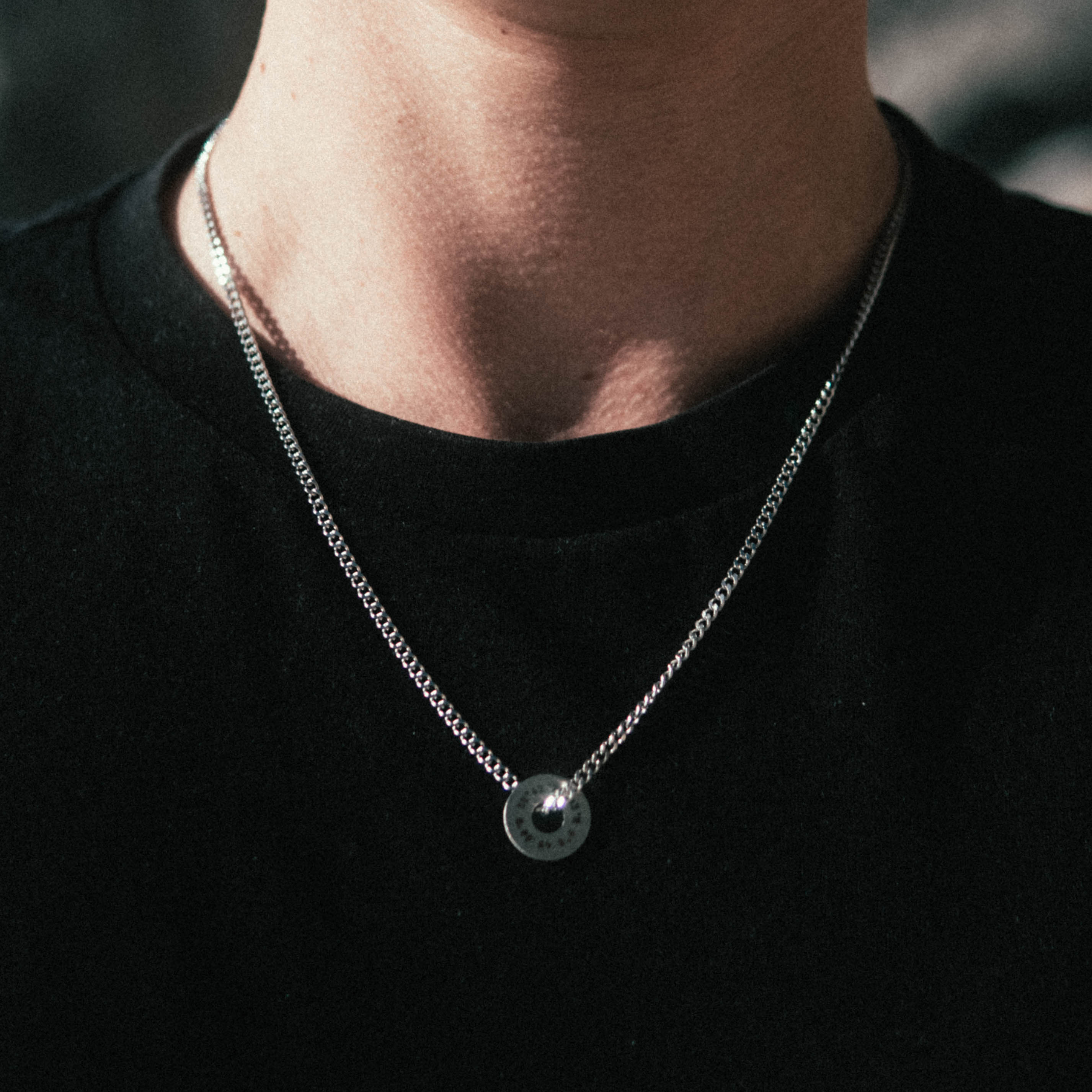 Custom Necklace Ring on a man's chest, made of stainless steel 316L with 18k gold PVD plating, customized and personalized with Morse code, coordinates, names, initials, dates, or custom text. Minimalist unisex jewelry, shoot on a beach in Portugal, Adraga.