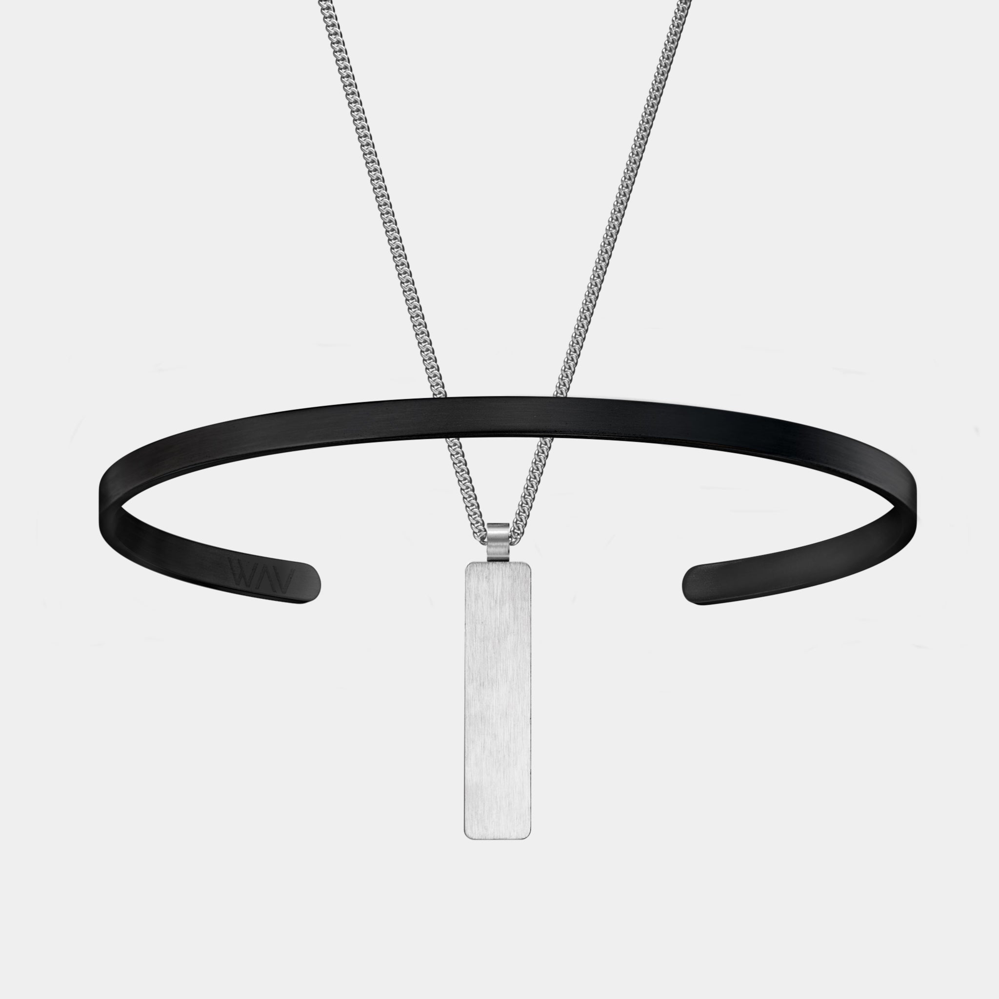 A minimalist image showcases WAVs Custom Cuff + Necklace Bundle, featuring a silver rectangular pendant alongside a sleek black open-ended cuff wristband on a plain white backdrop.