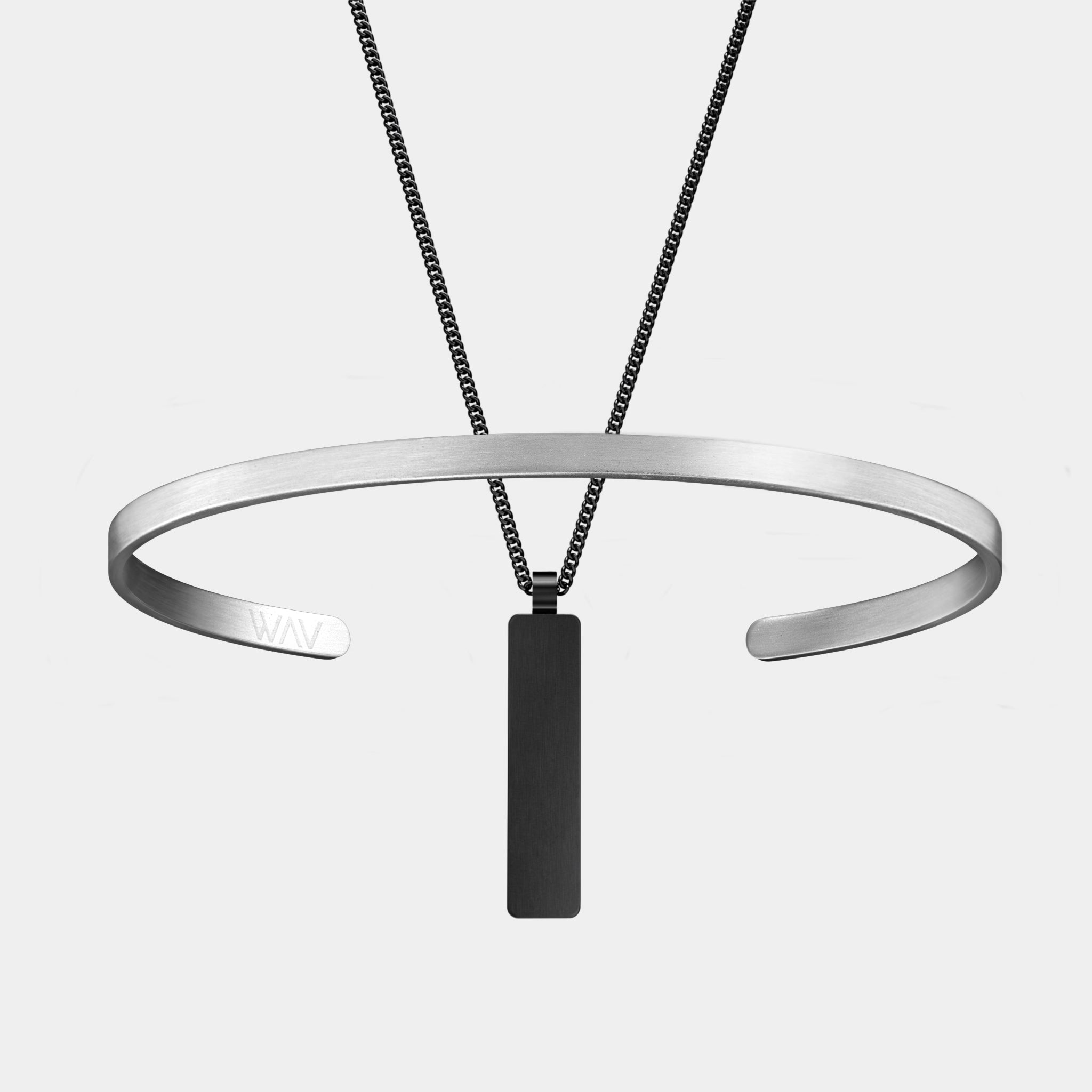Minimalist jewelry from WAV featuring the Custom Cuff + Necklace Bundle, which includes a sleek, open-ended cuff with subtle engraving and a black rectangular pendant on a fine chain necklace, set against a plain white background.