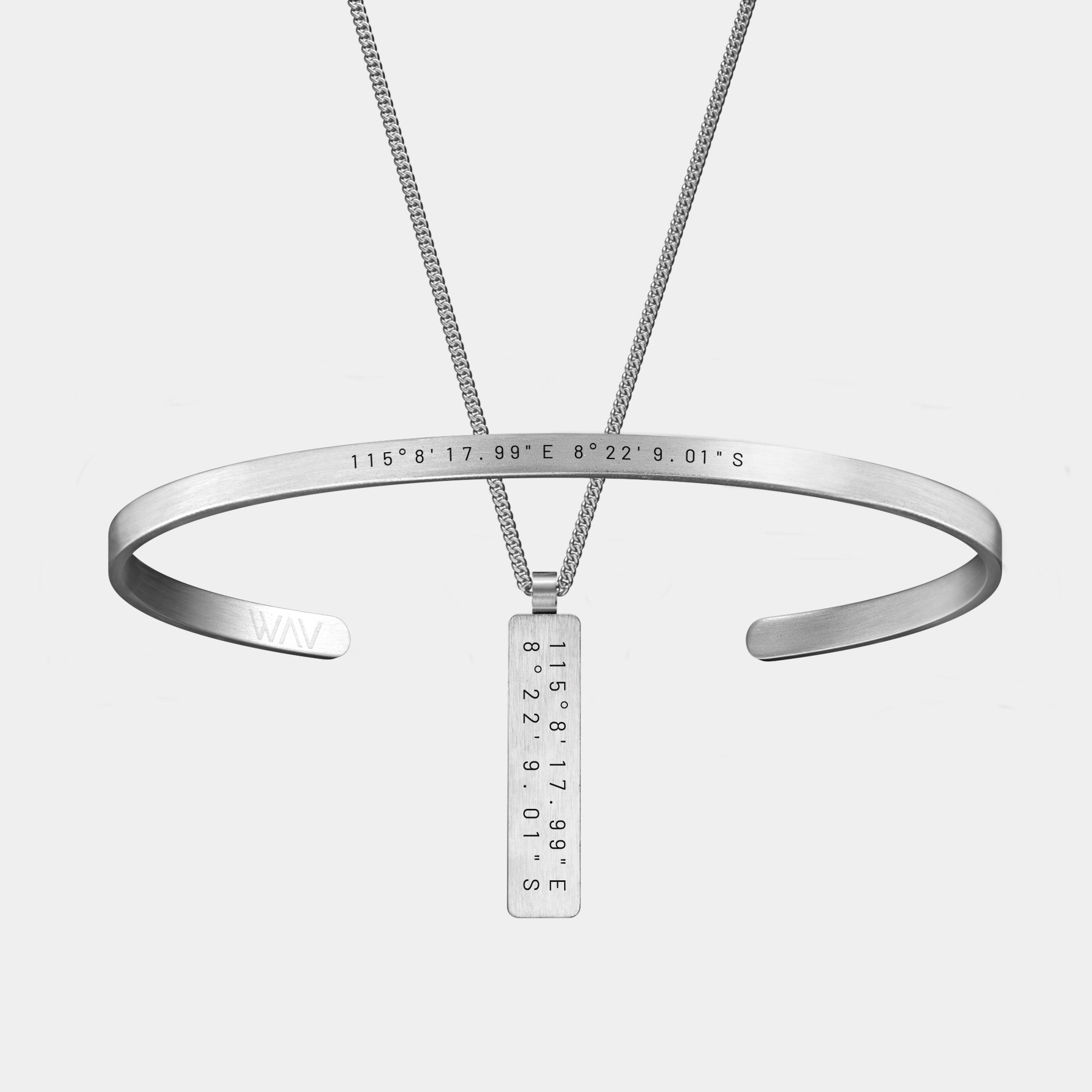The WAV Custom Cuff + Necklace Bundle includes a silver cuff bracelet and rectangular pendant necklace, both featuring engraved coordinates 115°817.99\E 8°229.01\S. The bracelet is personalized with WAV at the end.