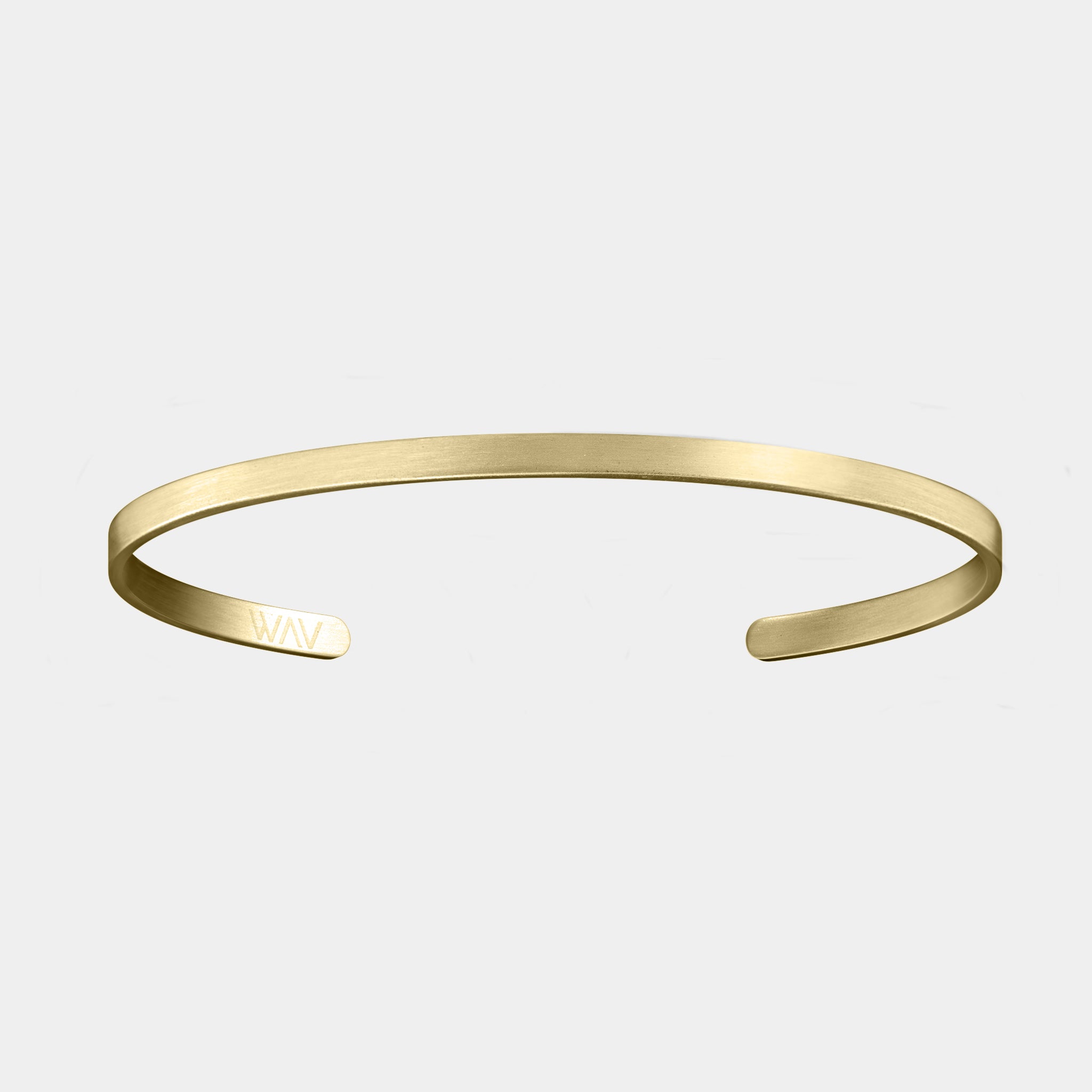 The Custom Cuff Bracelet by WAV is a minimalist gold-toned open cuff with a smooth finish and WAV initials engraved on one end. Ideal for personalized gifting, it is elegantly showcased against a light gray background.