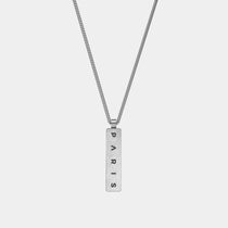 The WAV Custom Necklace Bar is a silver pendant with a vertical rectangular tag engraved with PARIS in black capitals on a simple, thin link chain, embodying the elegance of personalized jewelry against a plain white background.