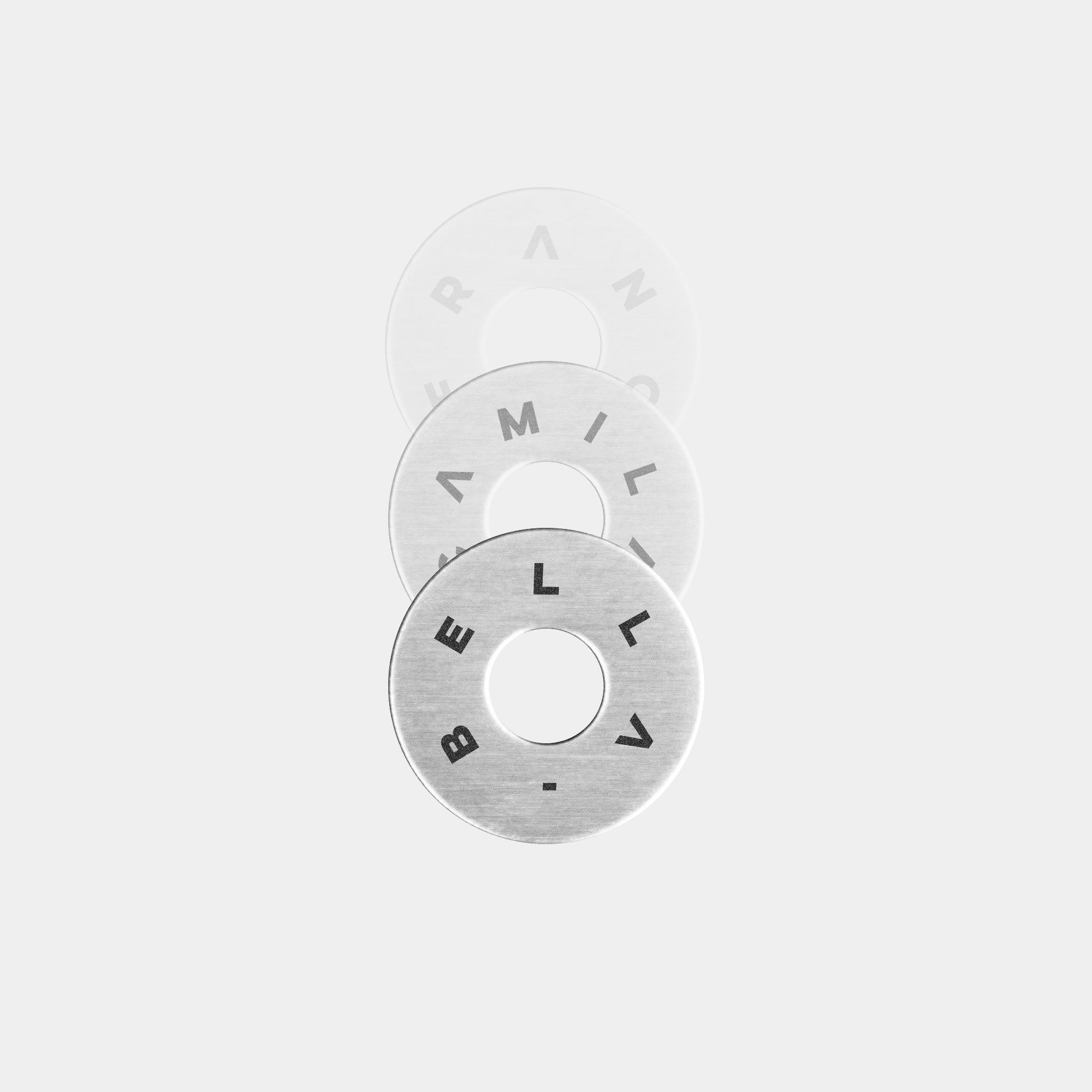 The Custom Extra Ring by WAV features three metallic washers engraved with names: BELLA in bold black on the front, AMILA in the middle, and FRANC on the back. Arranged vertically and partially overlapping on a light background, its a piece of personalized jewelry.