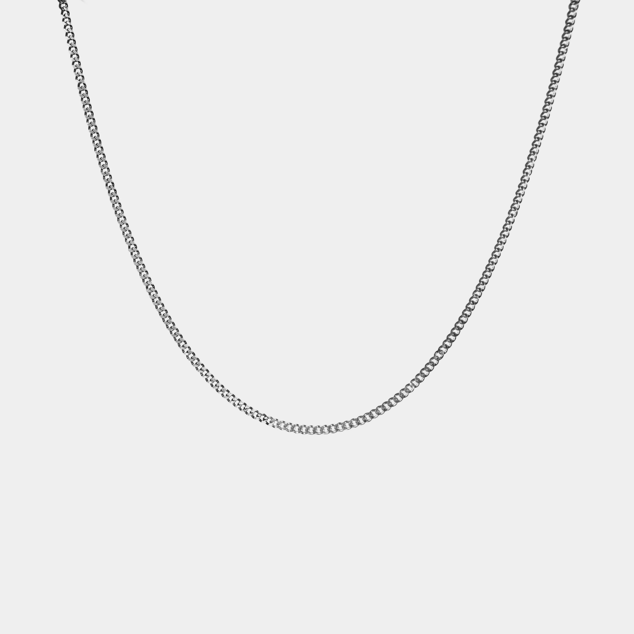 The WAV Cuban Chain Necklace, a personalized jewelry piece, features a delicate silver chain with small interlocking links forming an elegant curve, beautifully displayed against a plain white background.