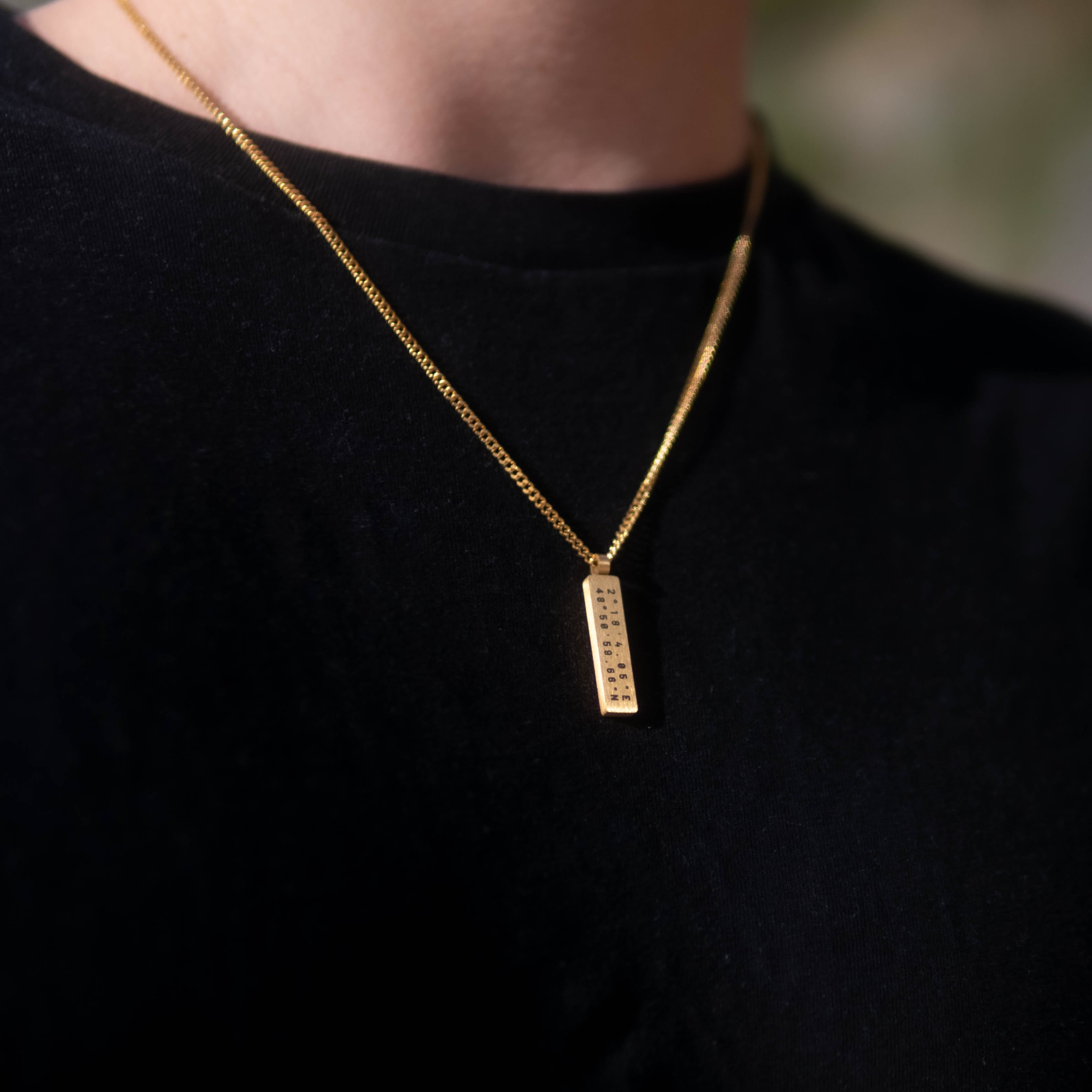 Custom Necklace on a man's chest, made of stainless steel with 18k gold PVD plating, customized and personalized with Morse code, coordinates, names, initials, dates, or custom text. Minimalist unisex jewelry, shoot on a beach in Portugal, Adraga Beach.