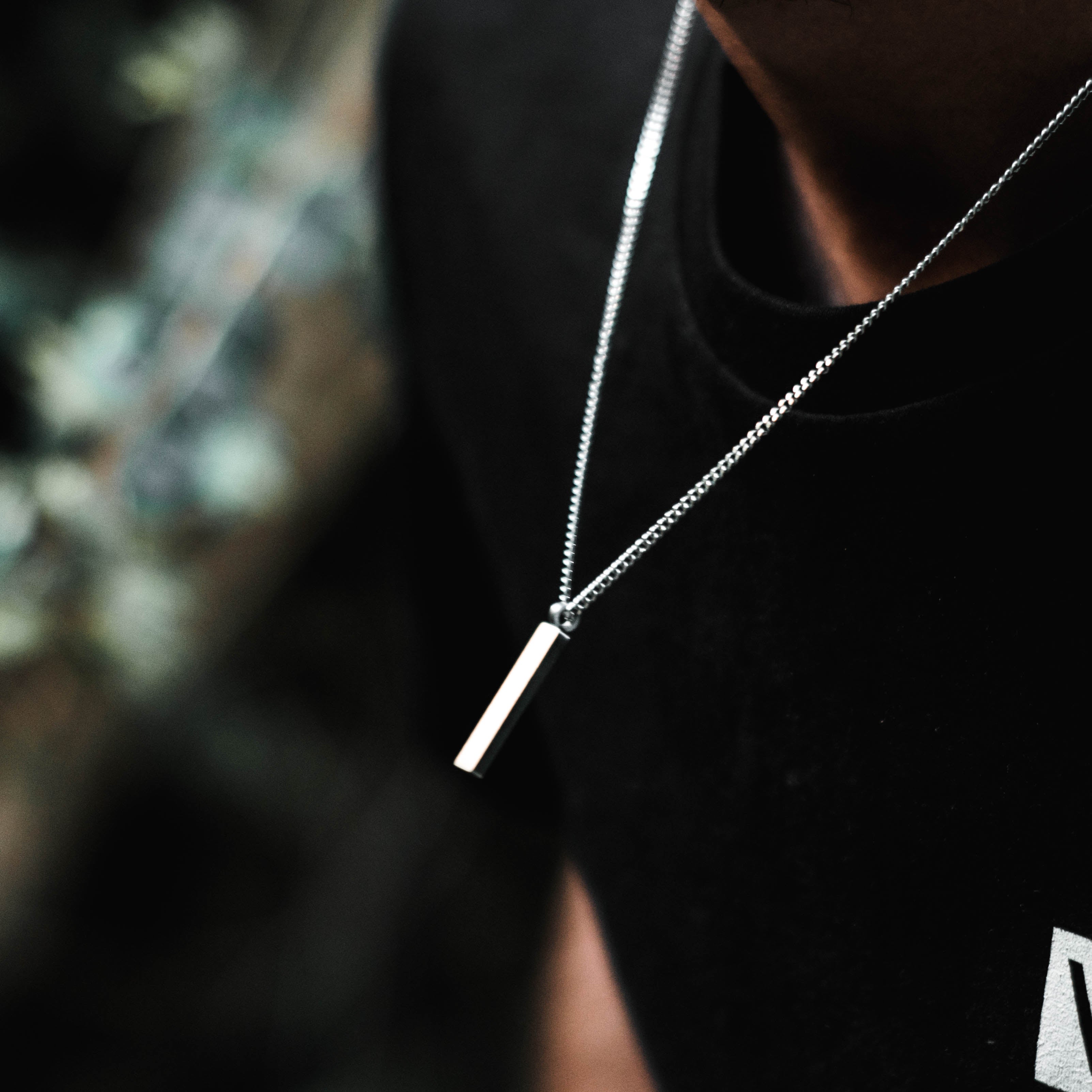 Custom Necklace on a man's chest, made of stainless steel 316L with 18k gold PVD plating, customized and personalized with Morse code, coordinates, names, initials, dates, or custom text. Minimalist unisex jewelry, shoot on a garden in Portugal, Sintra.